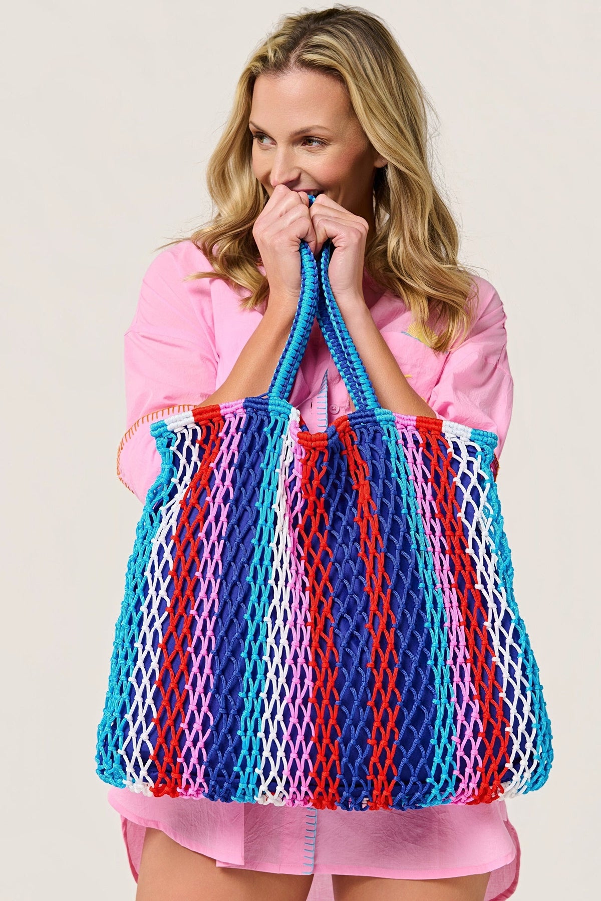 Model holding the Braziliana stripe tote up by both handles.