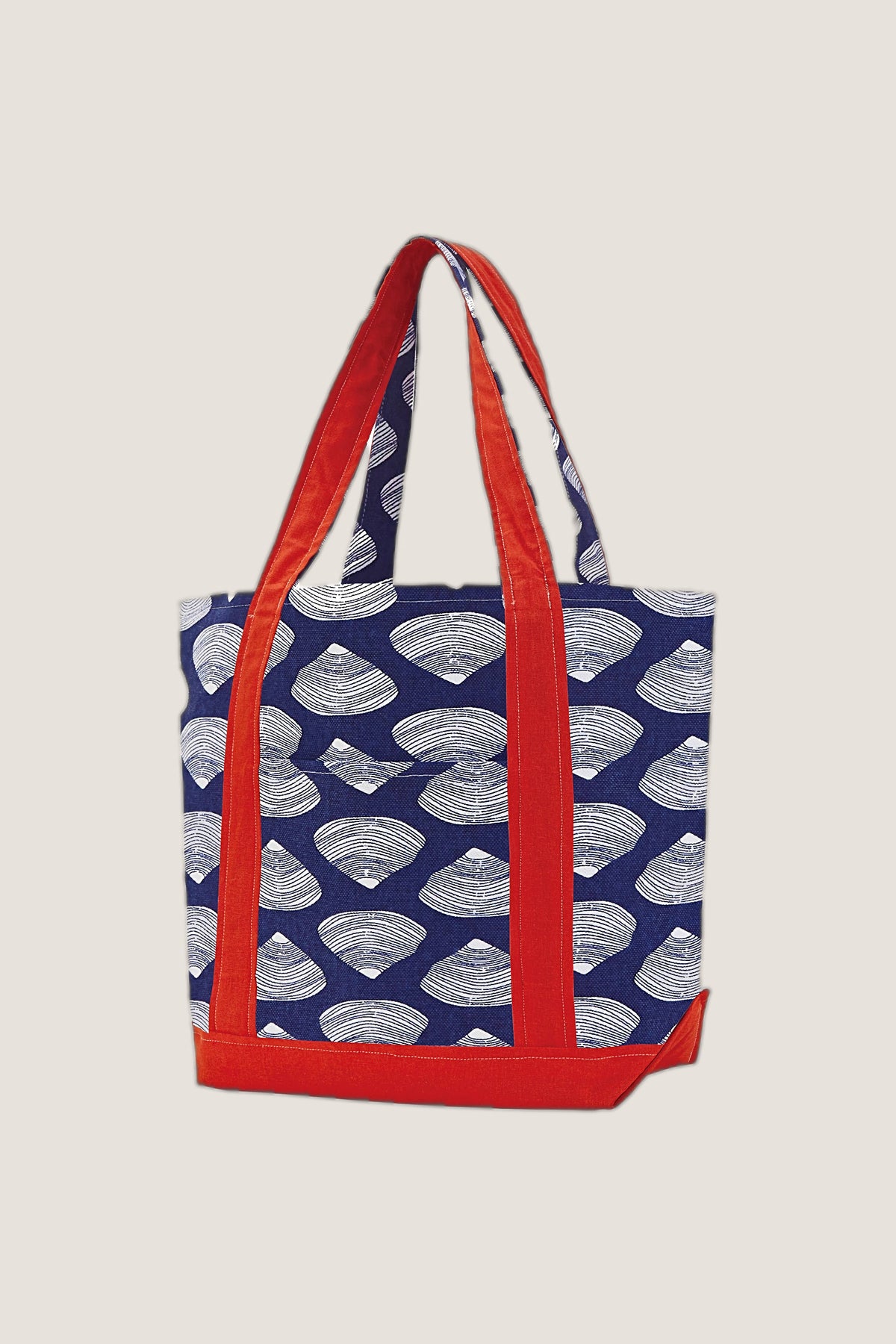The Clamshell Tote in navy with a white clamshell print and red handles and base, standing at a slight angle.