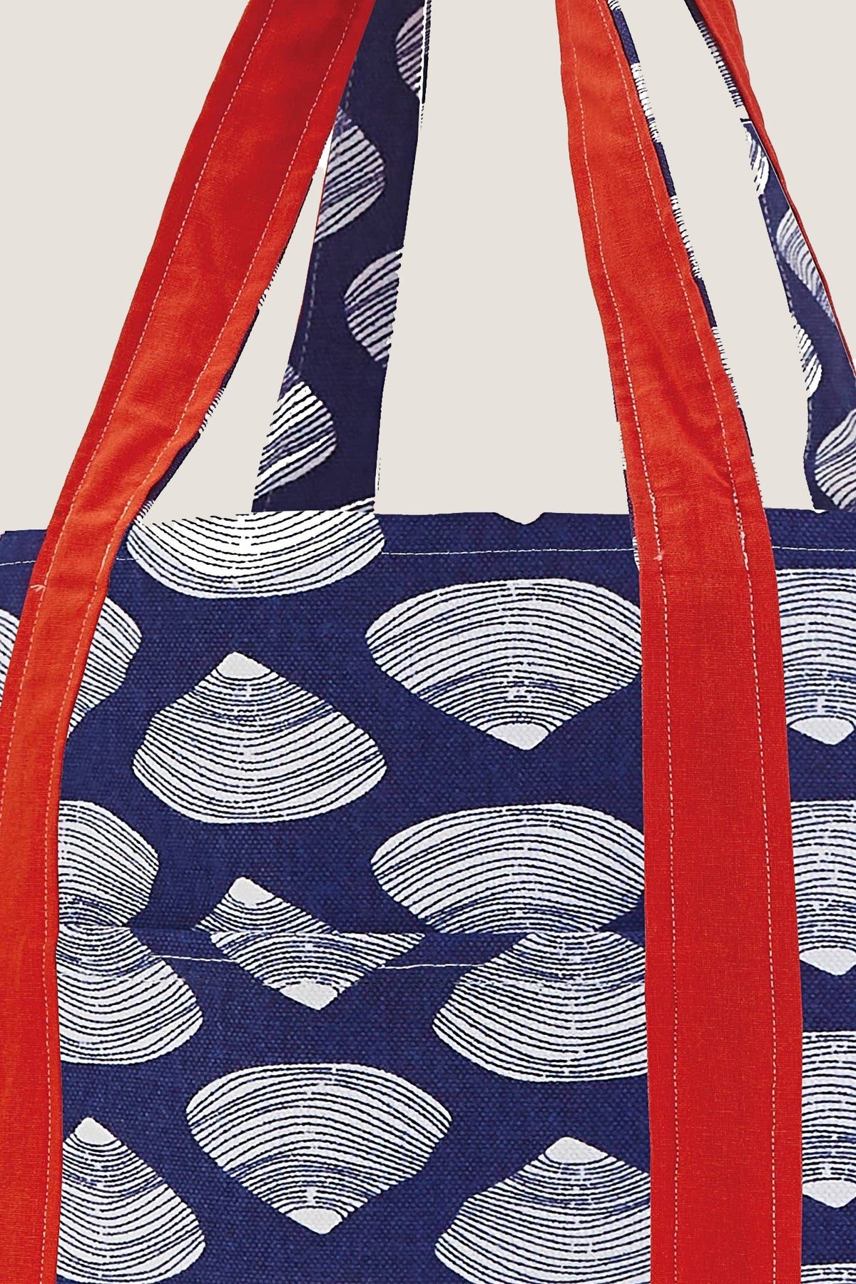 A close view of the Clamshell Tote's clamshell print, front slip pocket and red cotton handles.