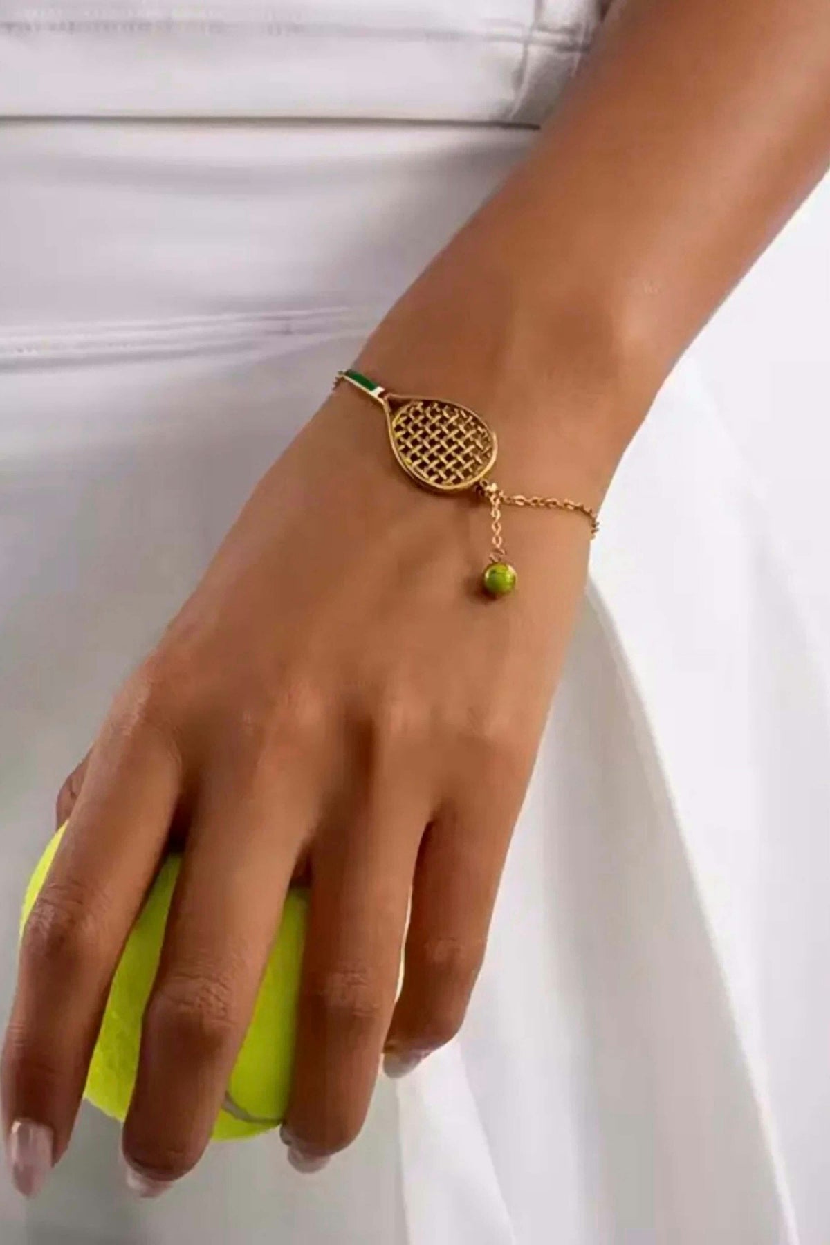 Country Club Tennis Bracelet worn on the wrist with a white tennis skirt, holding a tennis ball.
