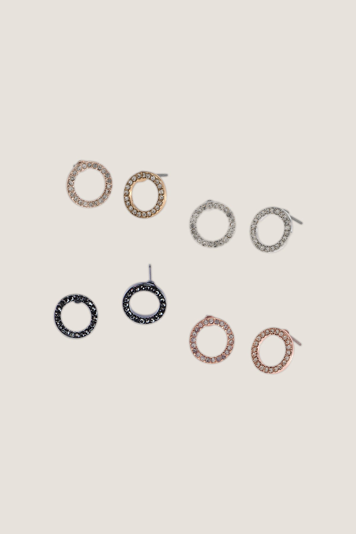 The Crystal Eternity circle stud earrings in four finishes, including gold, laid out on a warm background.