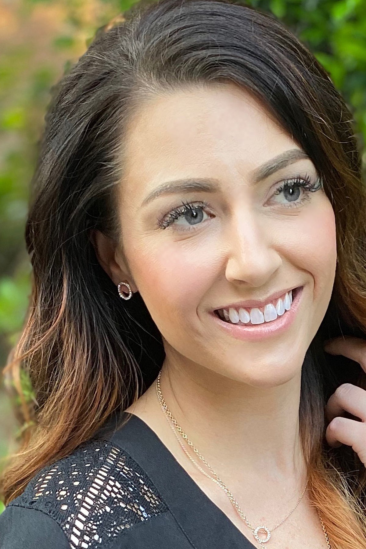 A smiling woman wearing the gold Crystal Eternity circle stud earring.