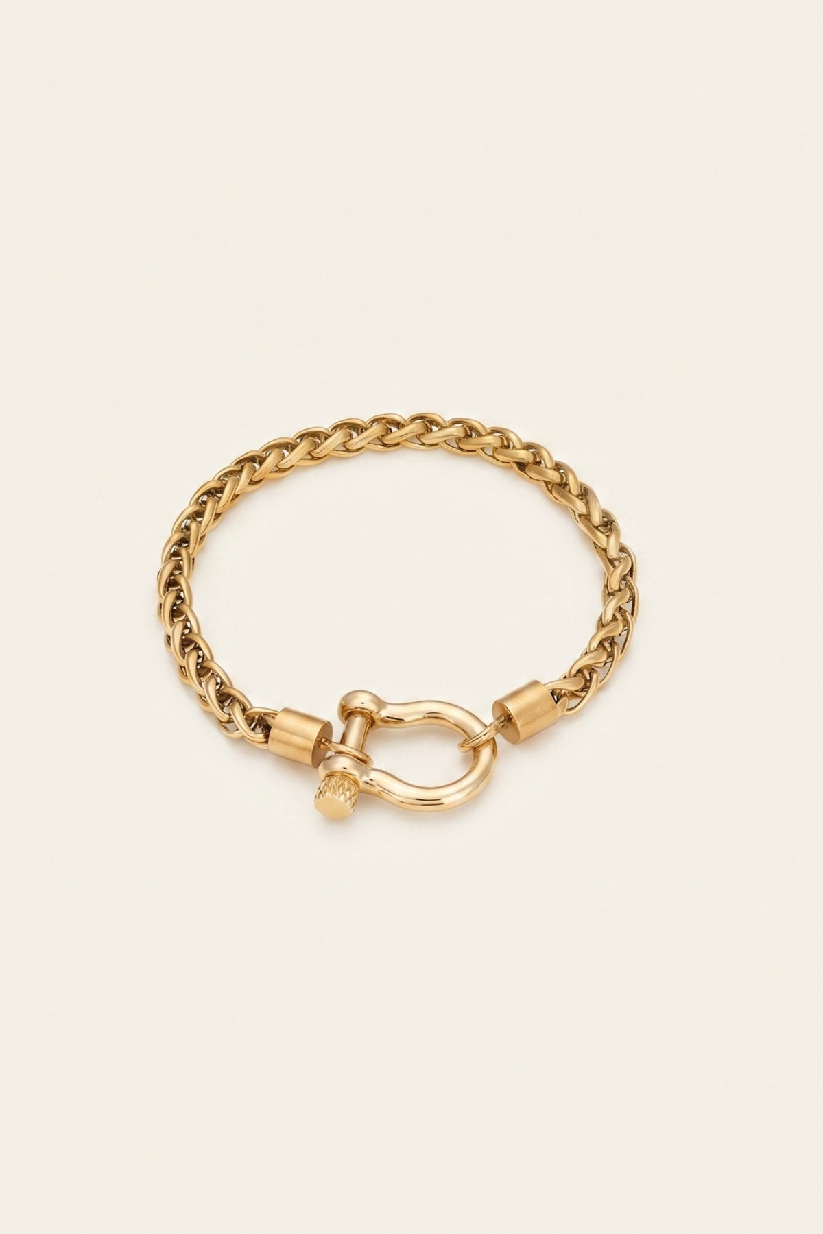 A gold-toned chain bracelet with a distinctive toggle clasp, displayed on a clean, solid off-white background.