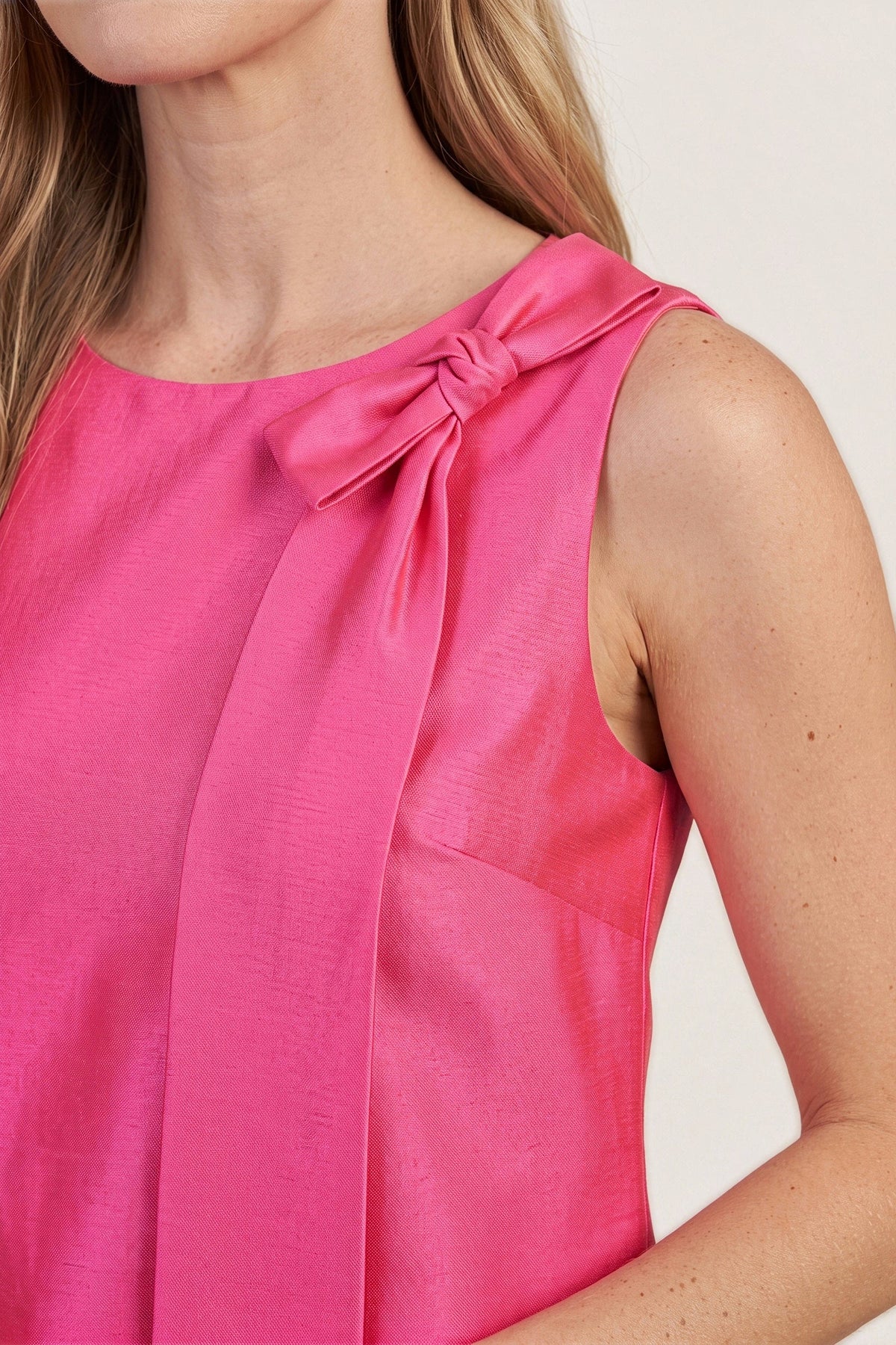 Close-up of the twisted satin bow at the neckline of the hot pink mini dress.