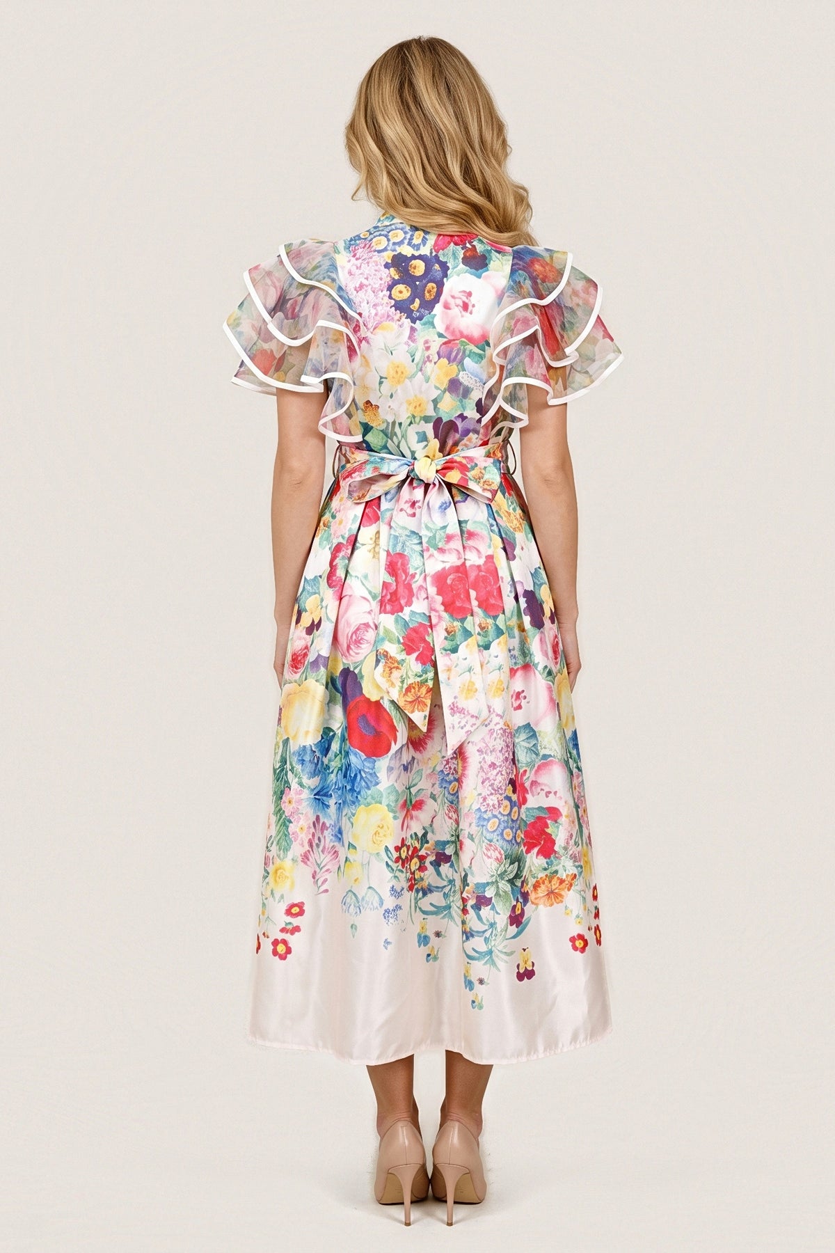 Back view of the Jardin Bloom Dress with the self-tie belt tied in a bow at the centre back, tiered ruffle sleeves and floral print fading to an ivory hem.