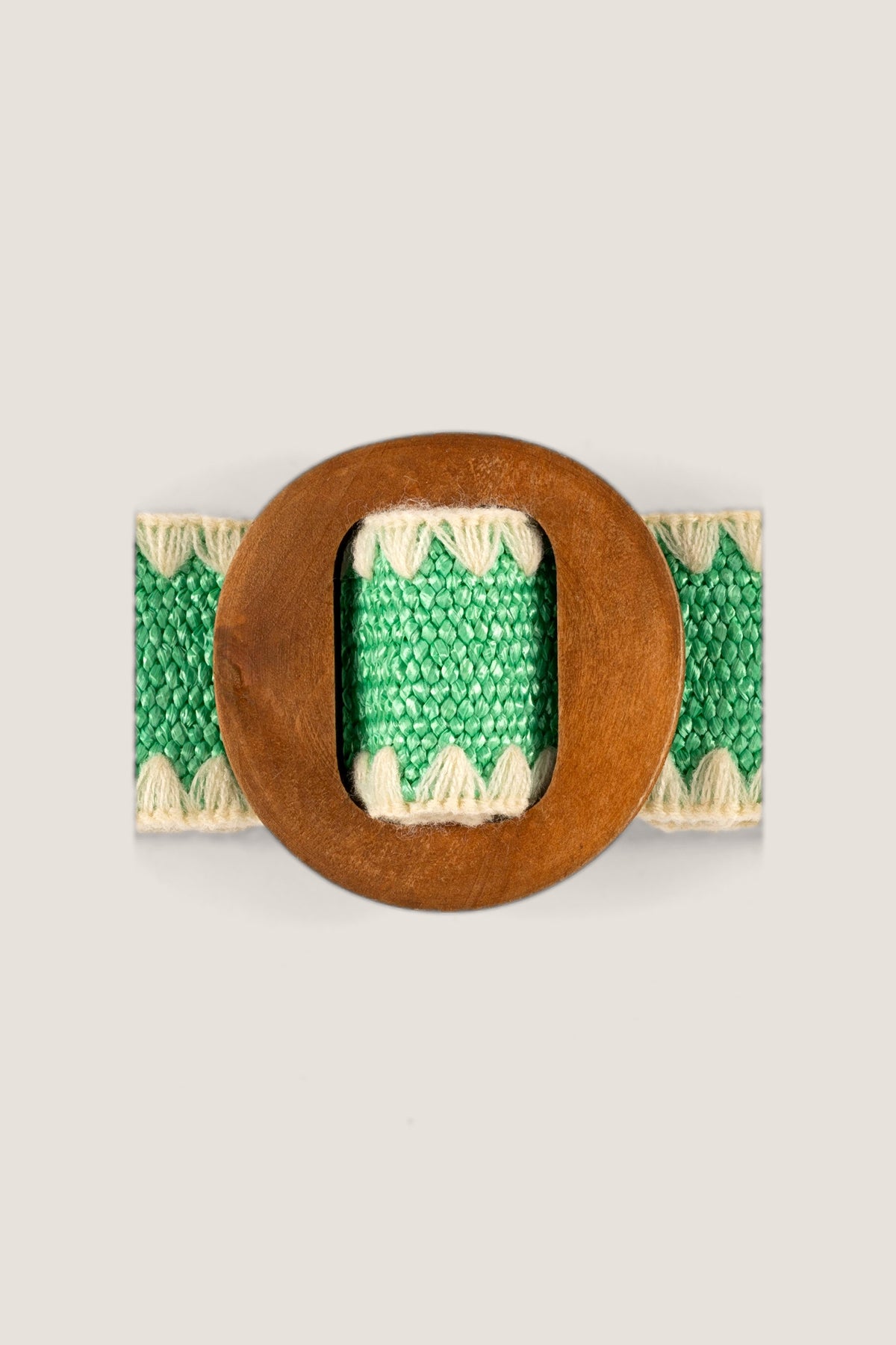A close-up of the Kayla Green Belt's round wood buckle and the green weave with cream zigzag trim.