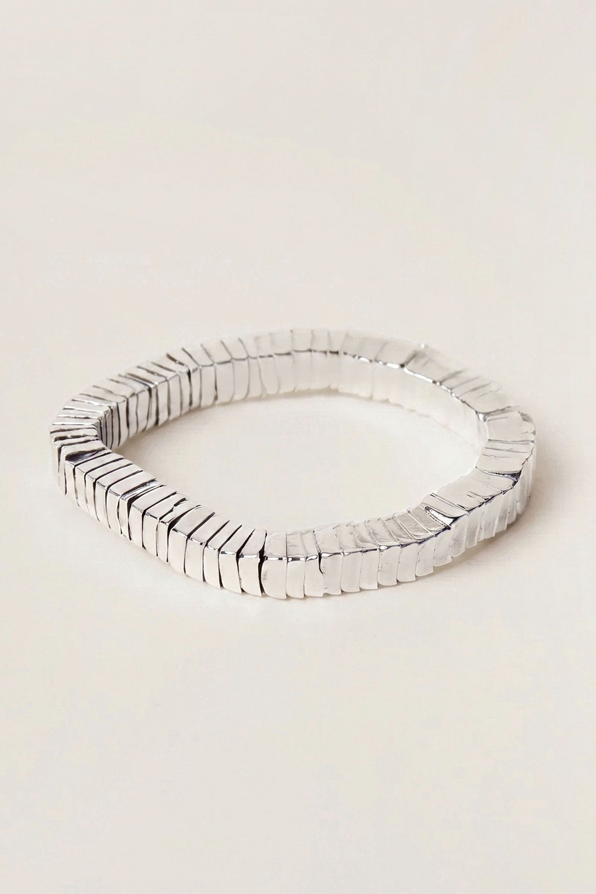 Lucille Silver Square Bead Stretch Bracelet in polished silver-tone plated brass, on a warm greige backdrop.