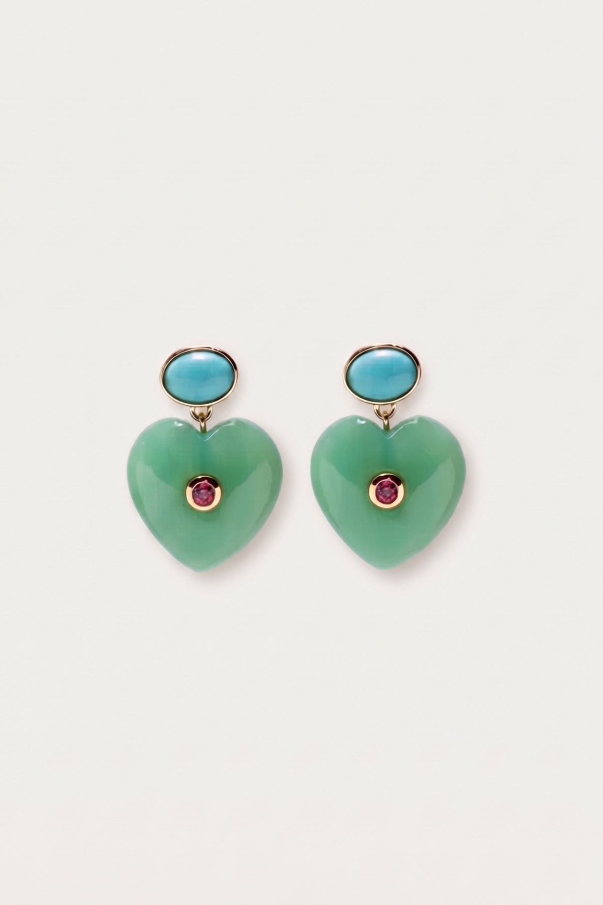 A pair of heart-shaped drop earrings featuring light green stone pendants with a small round pink gemstone at the center, suspended from gold-toned posts topped with oval light blue stones, set against a plain off-white background.