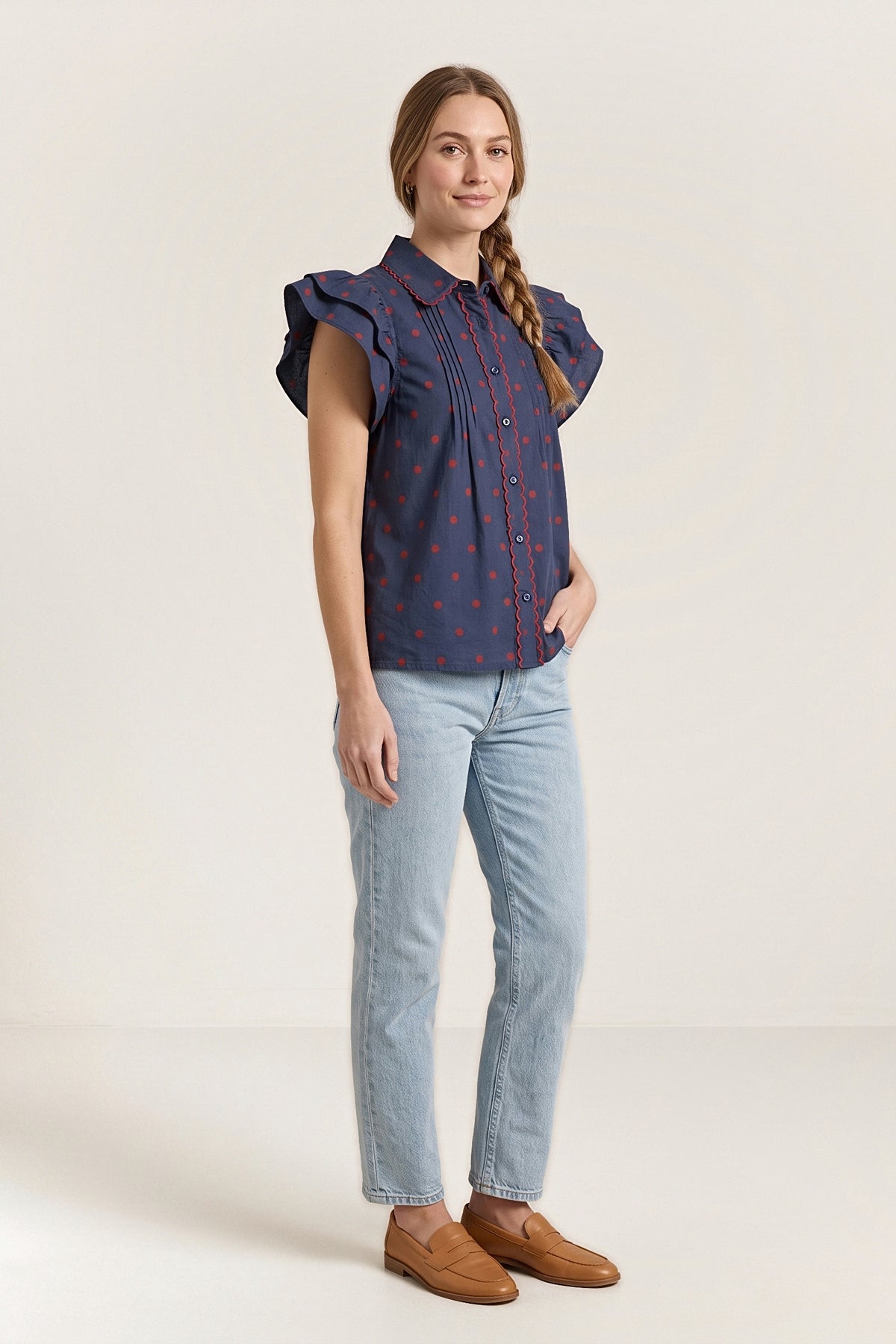 Three-quarter view of the navy sailmaker blouse, showing the flutter sleeve and scalloped trim.