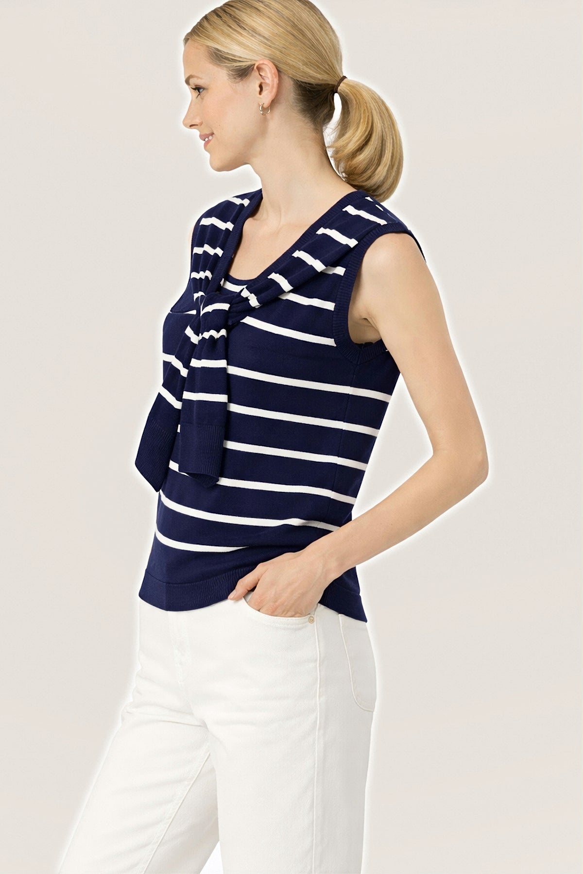 Three-quarter front view of the sleeveless navy and white striped knit sailor sweater with a tied sweater detail.