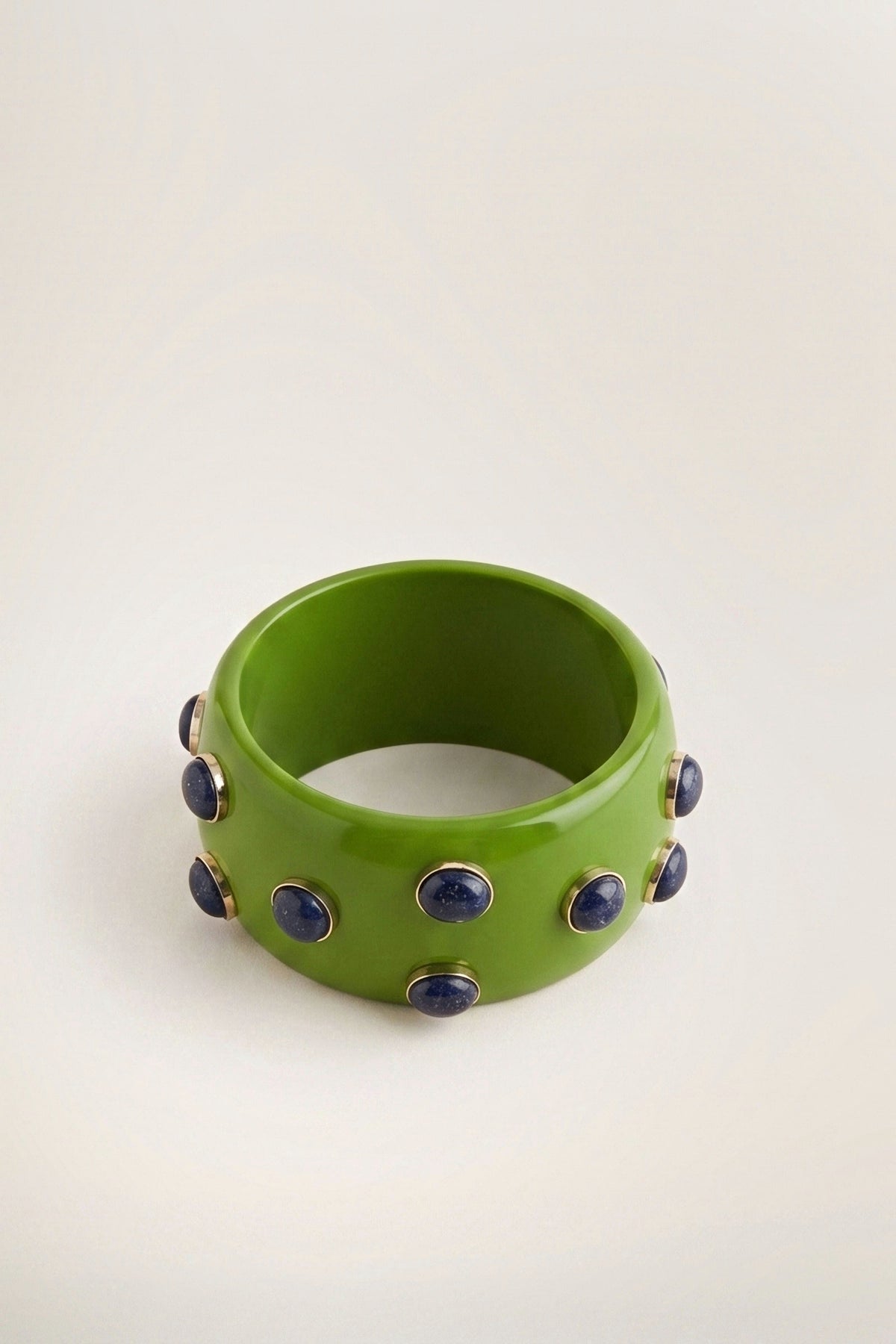 Side view of the Pea Amethyst Resin Bracelet, showing the width of the green resin bangle and its purple cabochon accents.