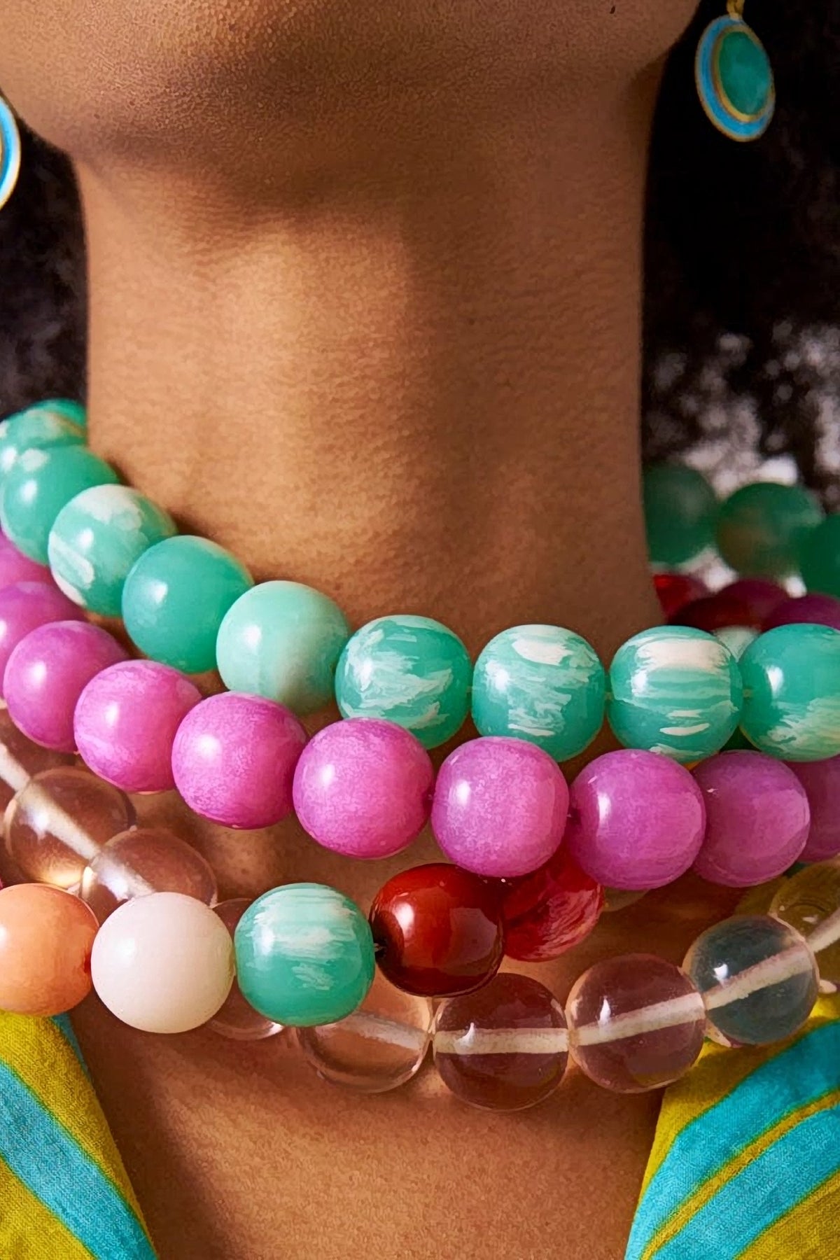 Close-up of the Purple Iris resin bead necklace stacked with mint, clear and coral Iris necklaces at the base of the neck.