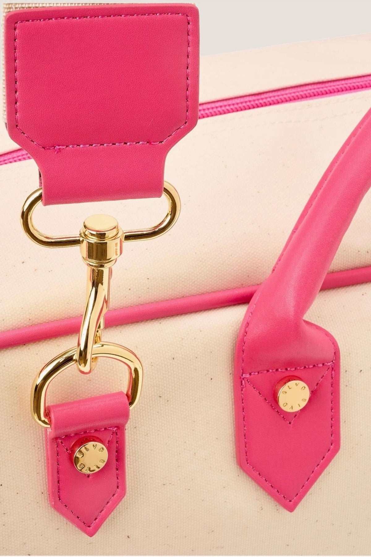 A close view of the Raspberry Margo tote's hot pink leather tab and gold strap clip.