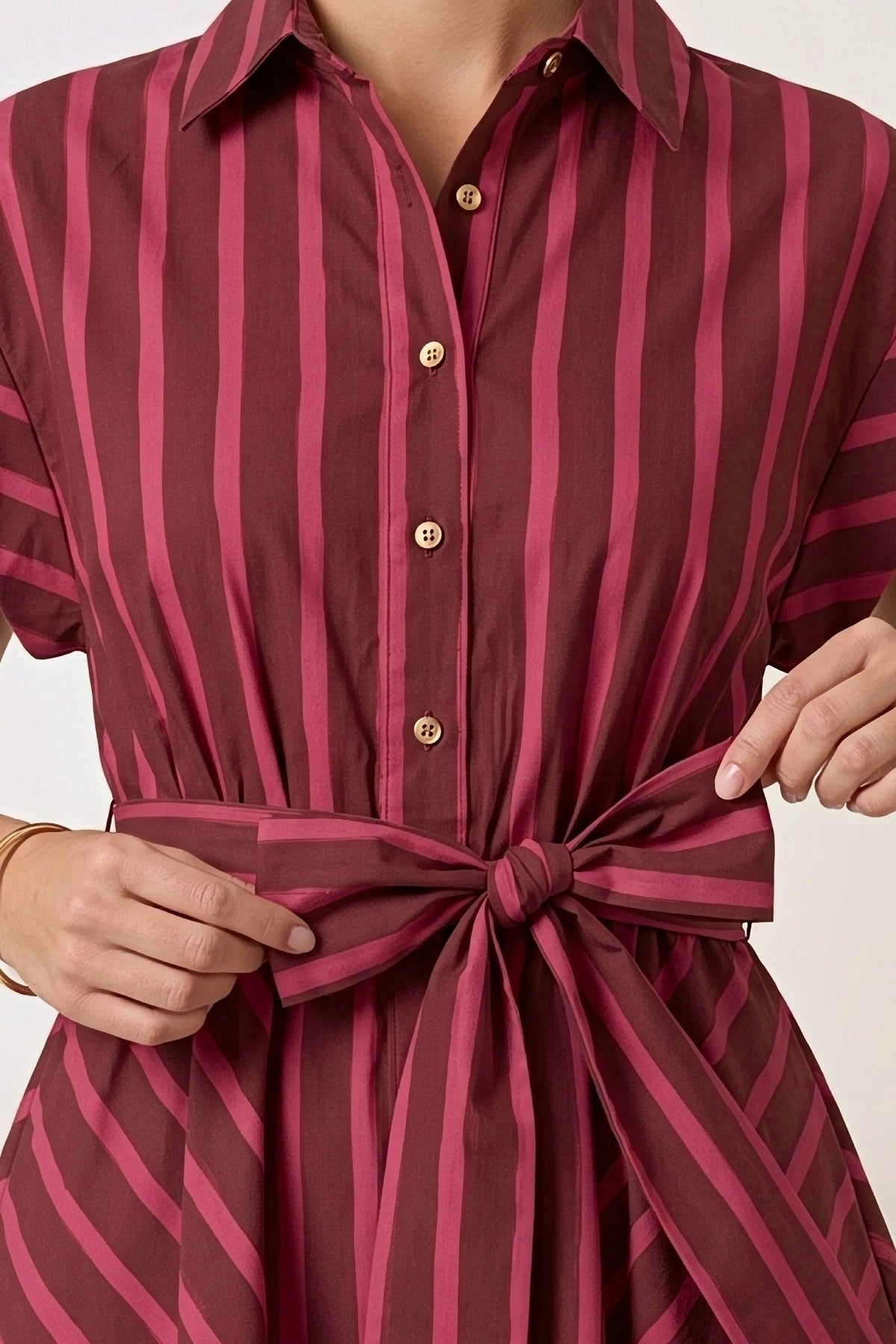 Close-up of the Raspberry Ribbon dress: pointed collar, gold buttons and the self-tie bow at the waist.