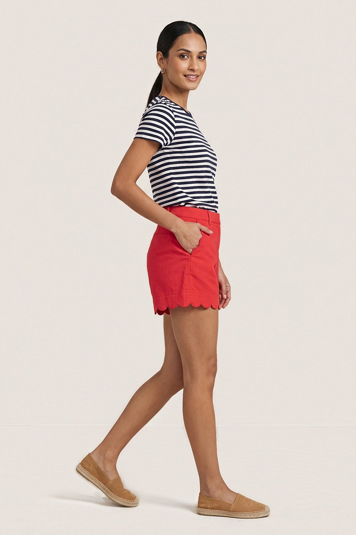 Side view of the Red Harbor scallop shorts in motion, one hand in the front patch pocket.