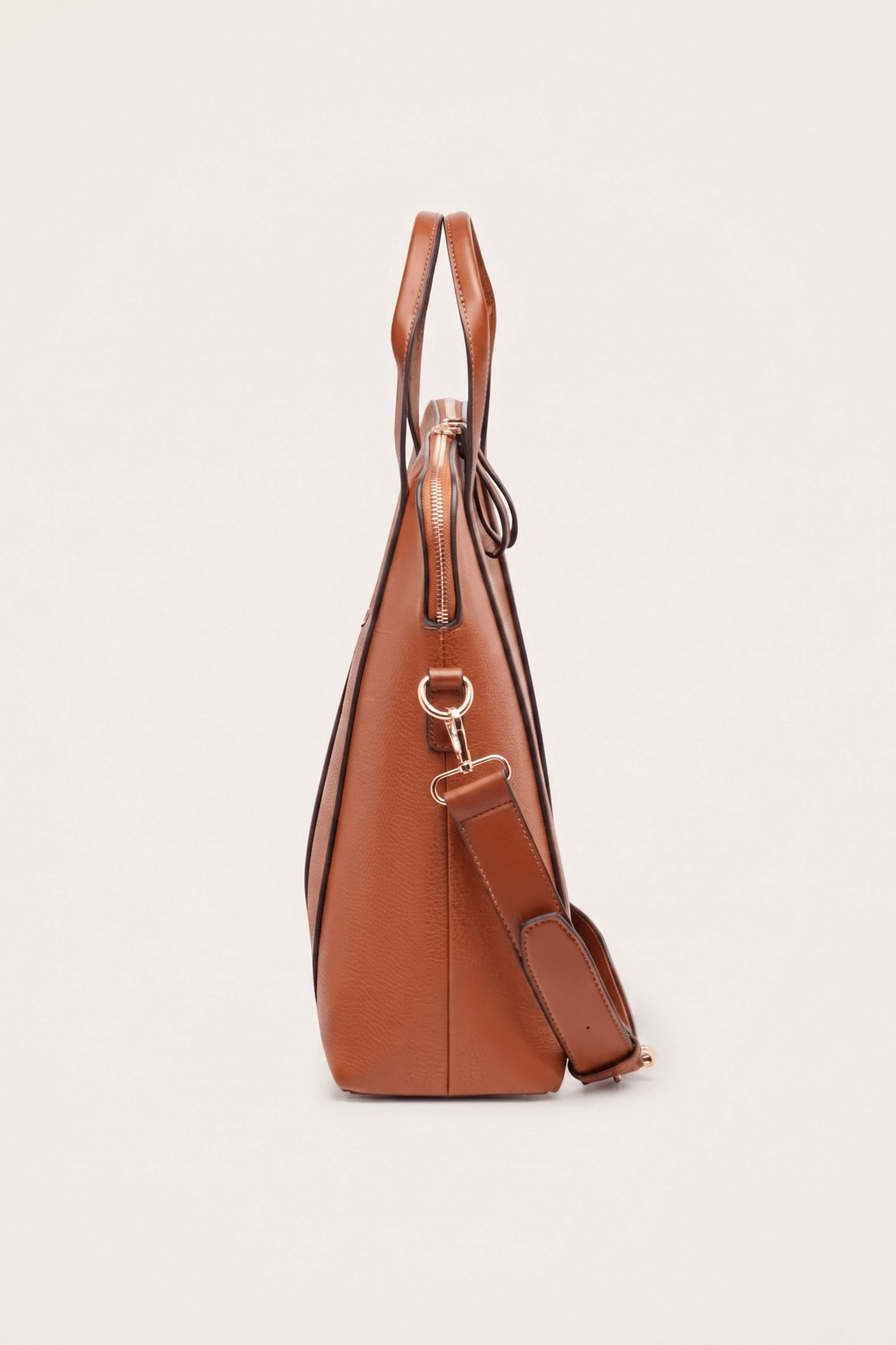 A side profile view of a brown leather handbag with a matching shoulder strap and gold-tone hardware, set against a solid off-white background.