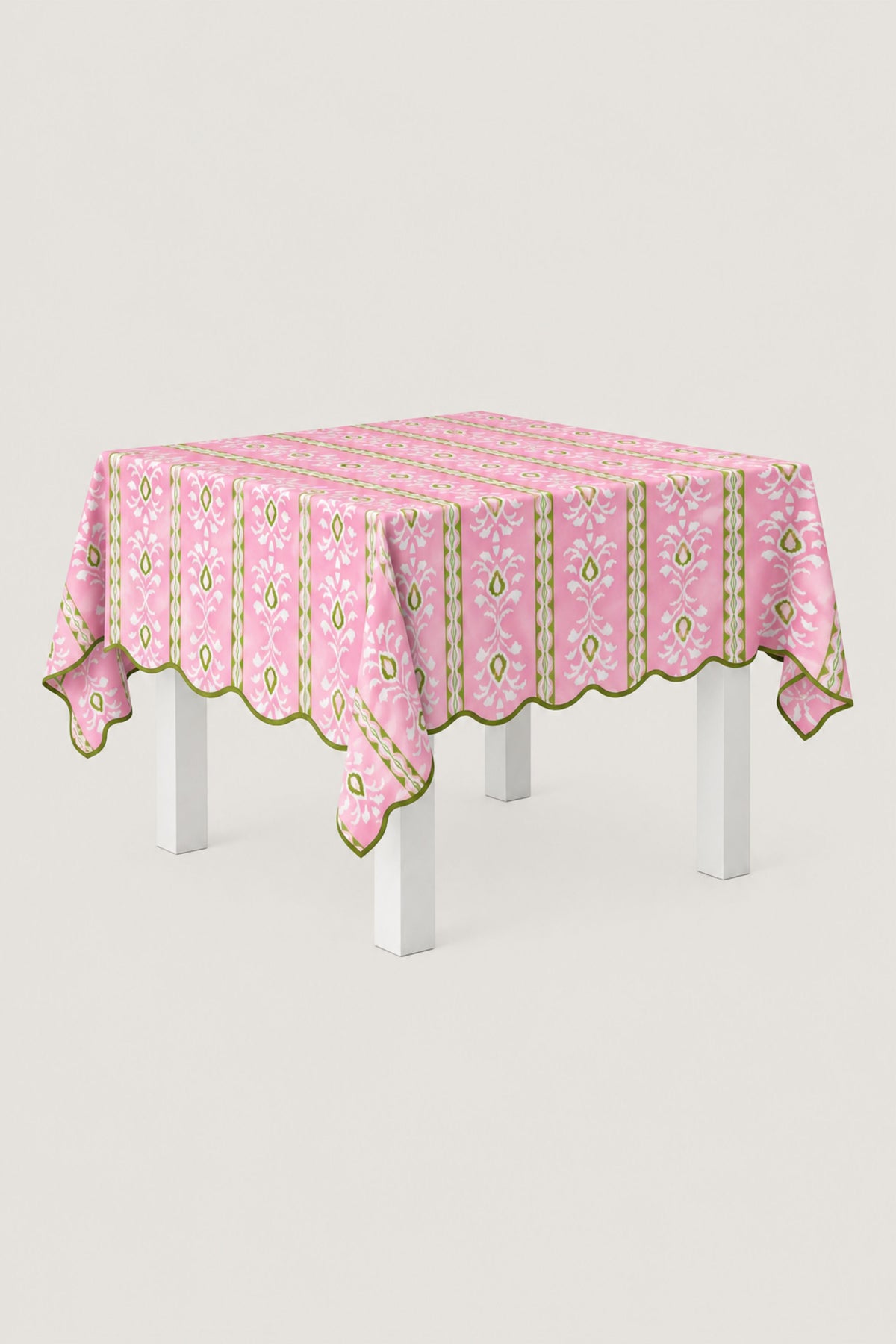 A pink tablecloth with a green and white vertical patterned design and scalloped edges, draped over a white table against a light gray background.