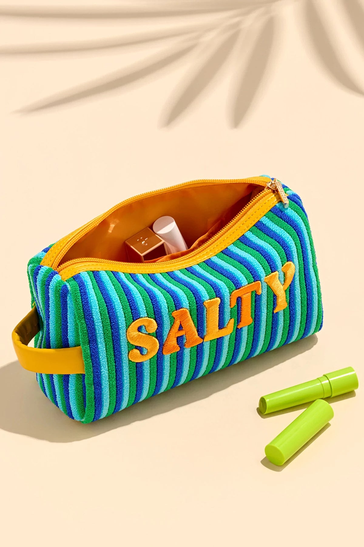 The Salty zip pouch open, showing the orange lining with lipsticks inside.