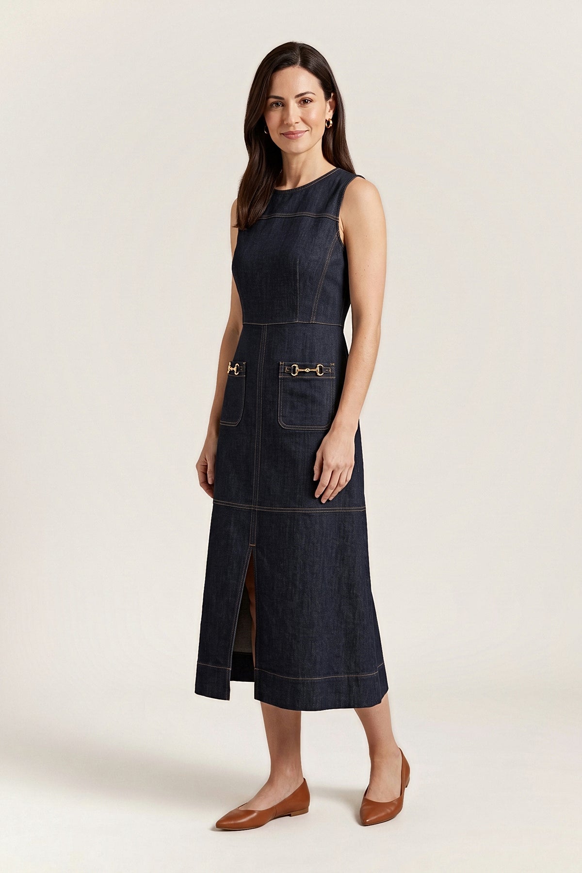 Three-quarter view of the dark denim midi dress, showing the horsebit pockets and front slit.