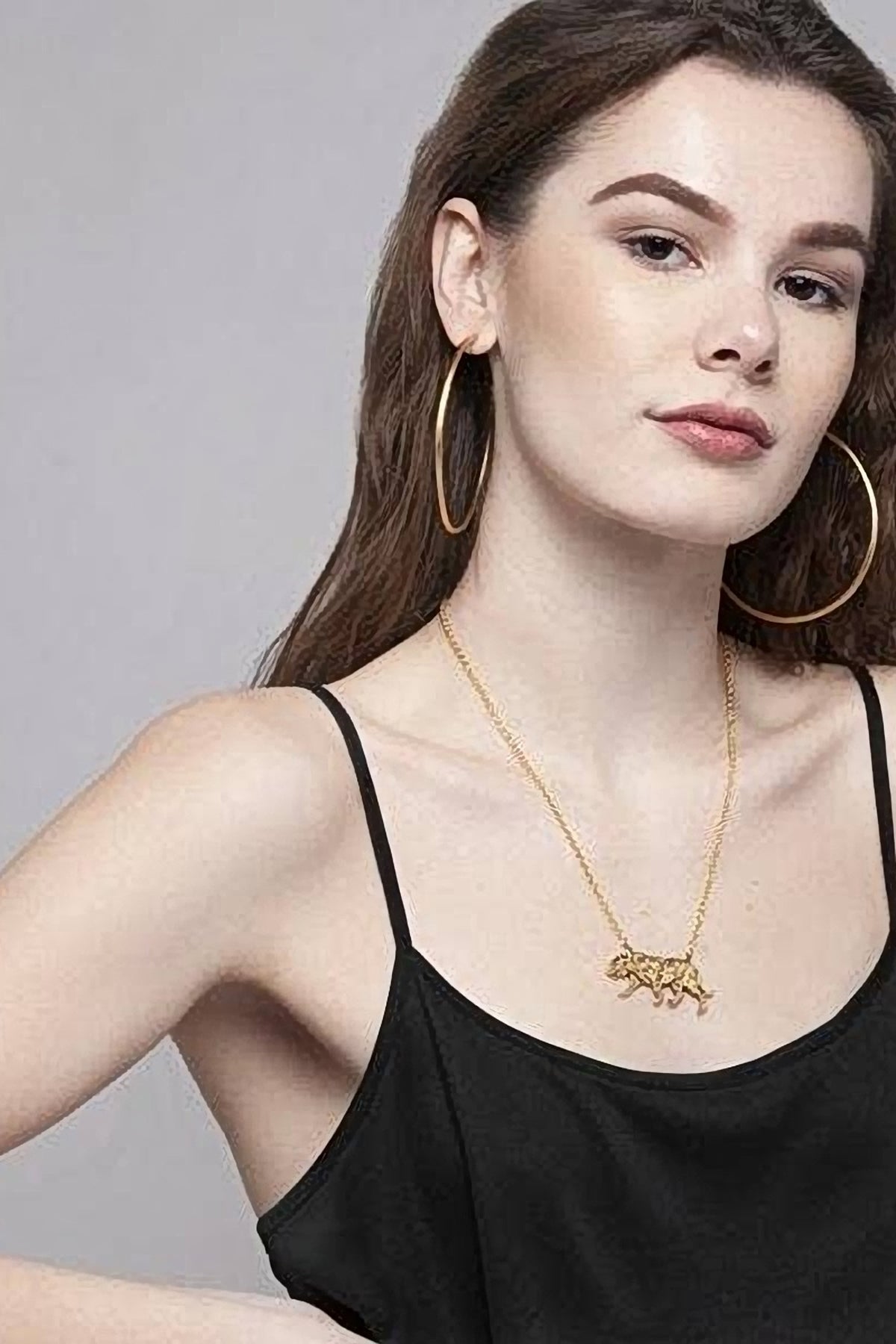 Model in a black camisole wearing the gold Tiger Necklace, the tiger pendant resting above the neckline.