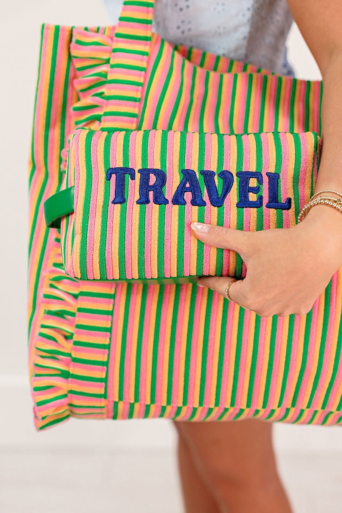 The Travel zip pouch held flat in front of the matching tote, lettering facing out.