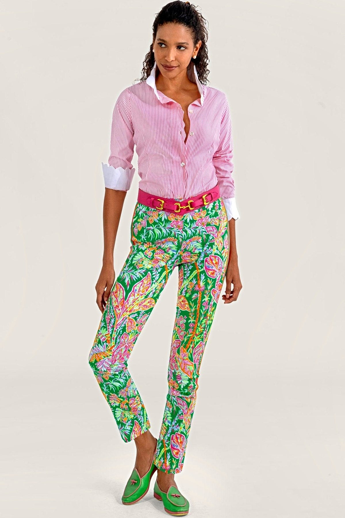 A woman in a pink striped shirt, pink belt and kelly green vine print pull-on pants.