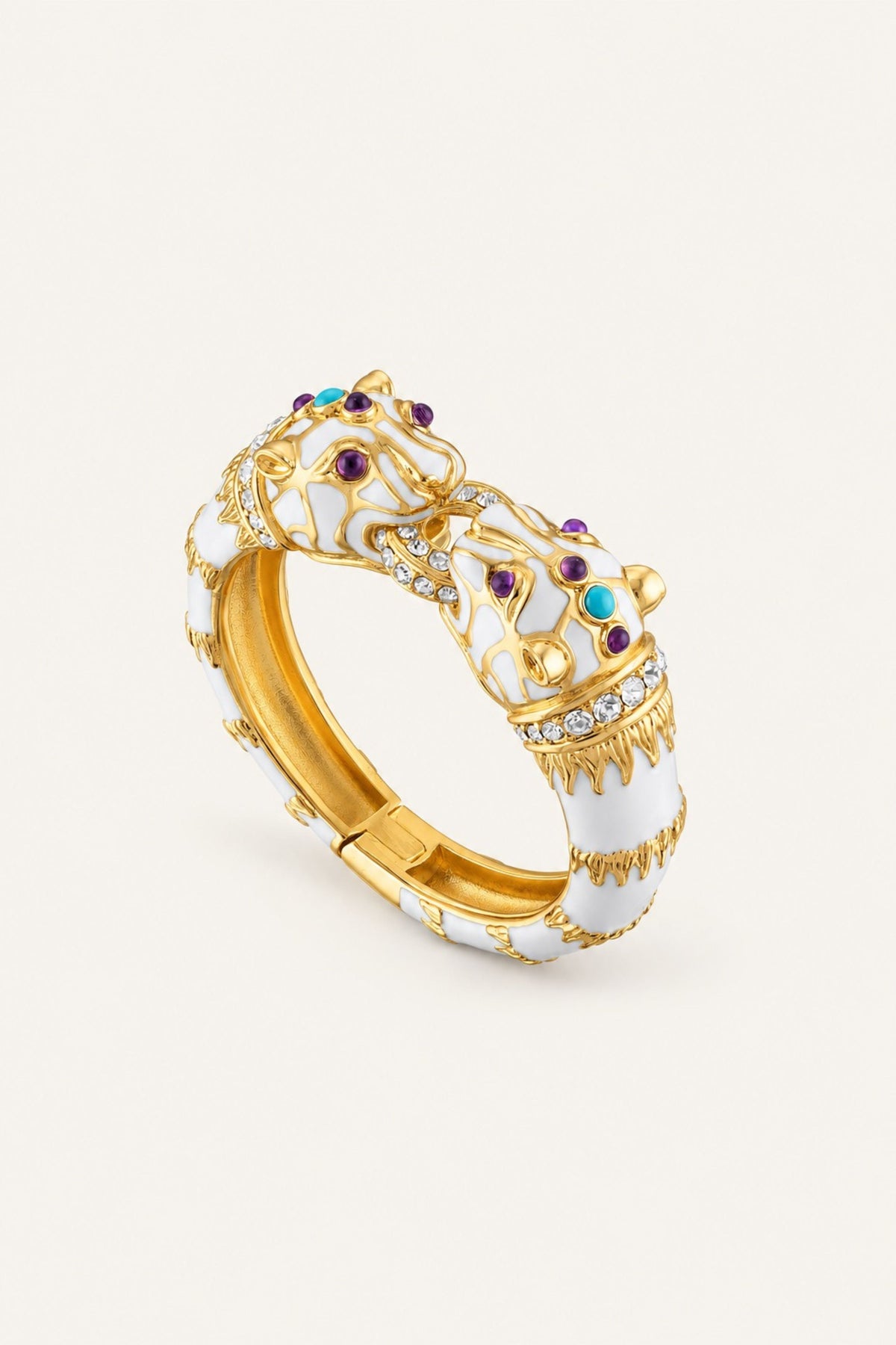 A gold and white enamel tiger cuff bracelet with colorful enamel accents and small clear stones, shown on a light cream background.