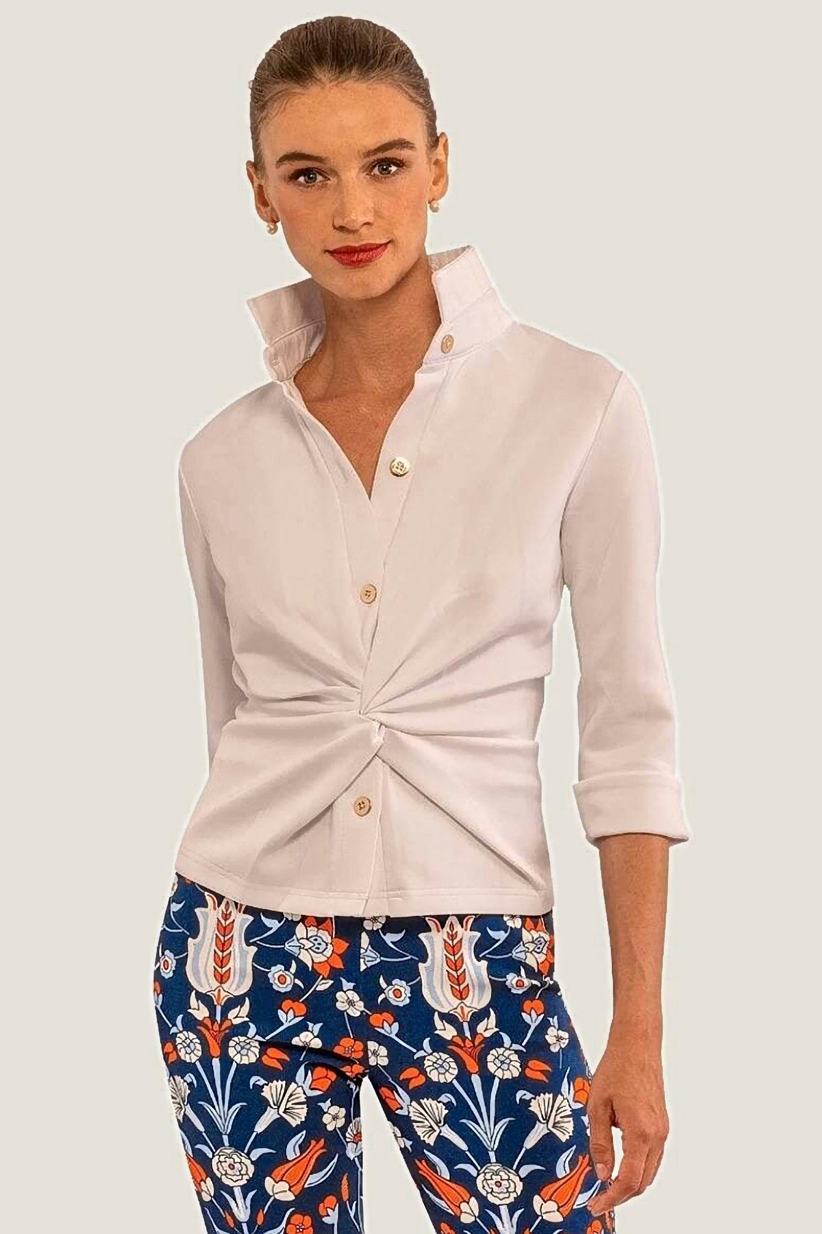 Woman wearing a white long-sleeve shirt and blue floral pants on a white background