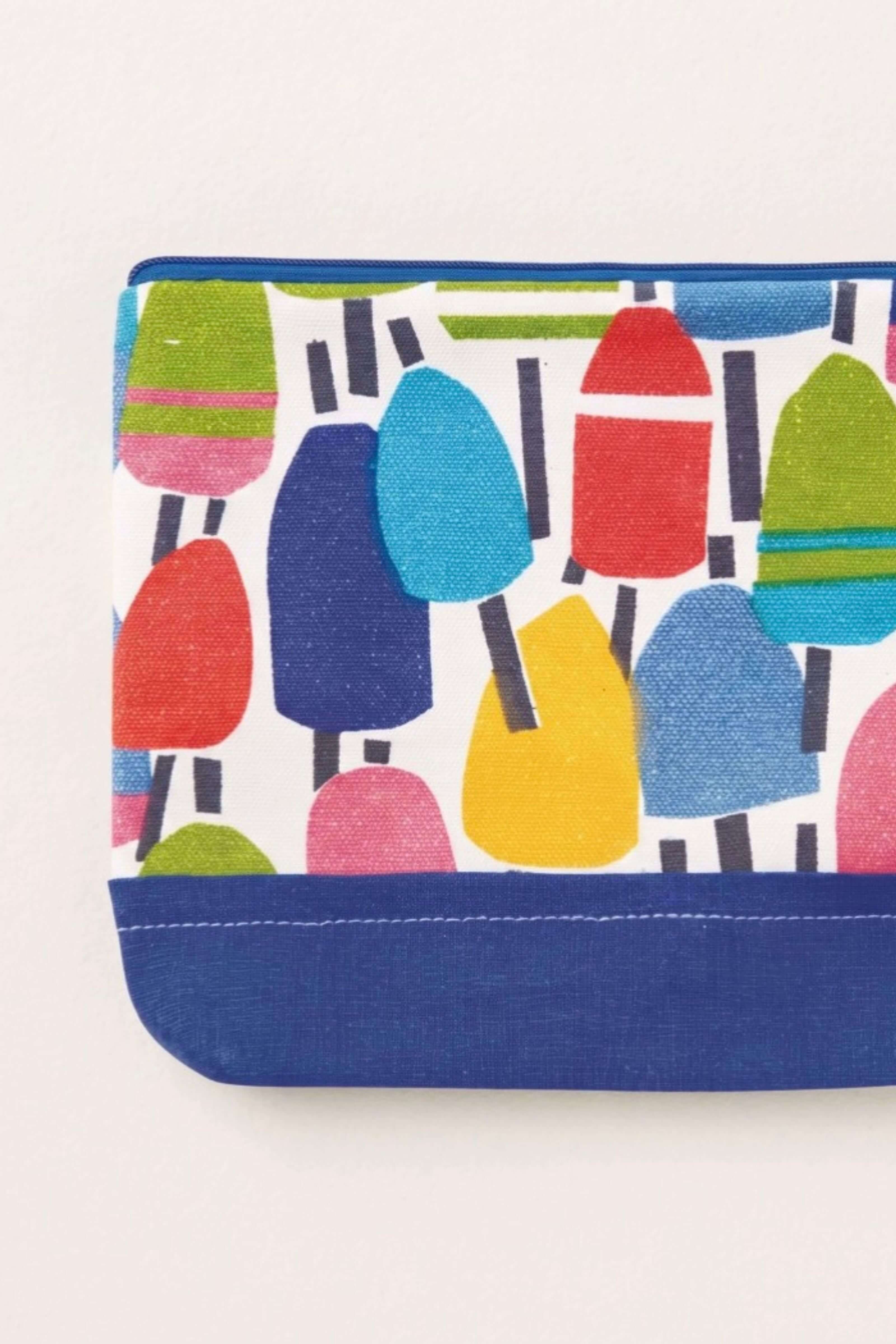 A close-up of a fabric pouch or clutch with a colorful popsicle print on a white background and a solid navy blue bottom border.