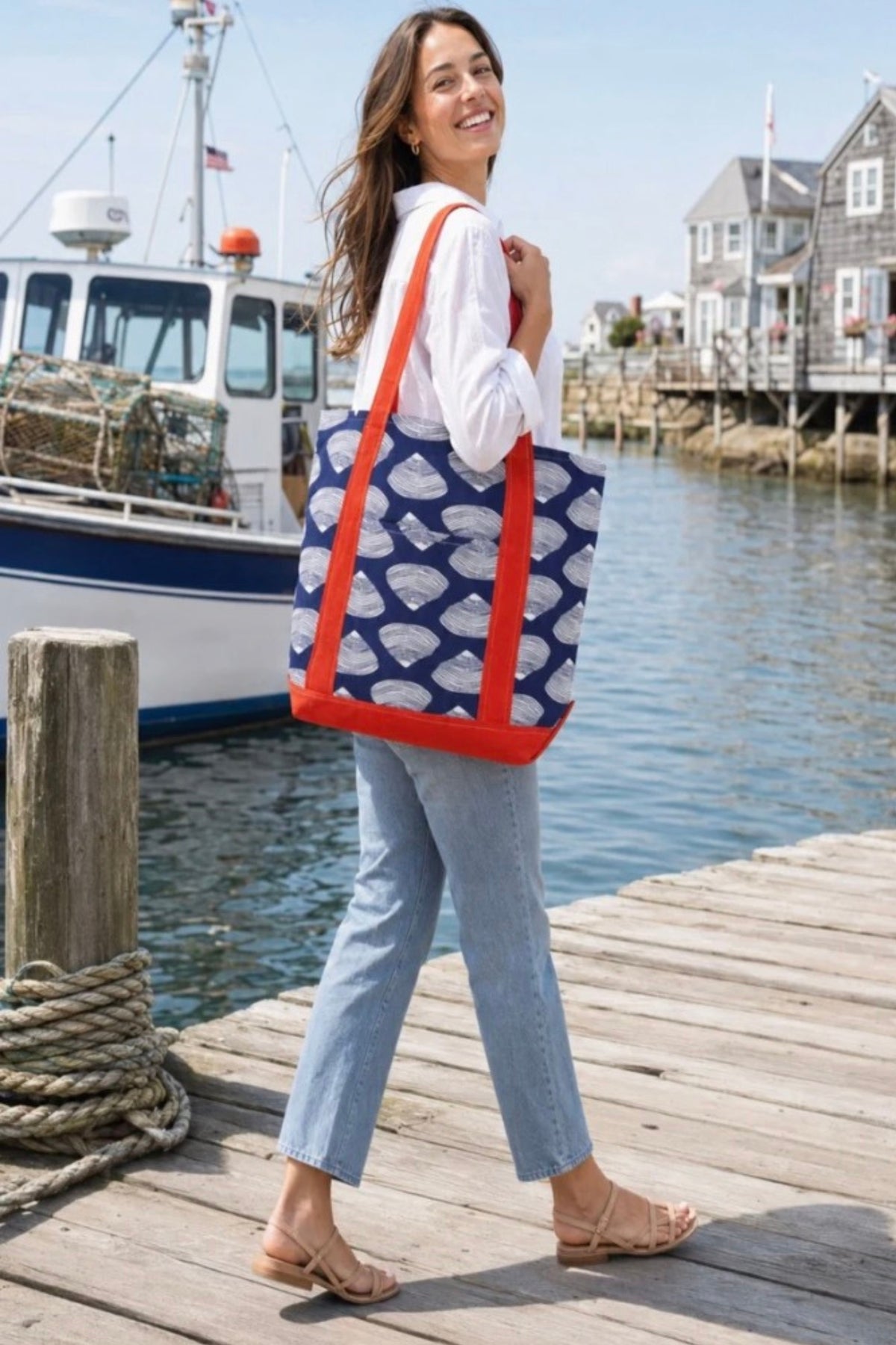 A woman on a harbour dock carrying the Clamshell Tote on her shoulder.