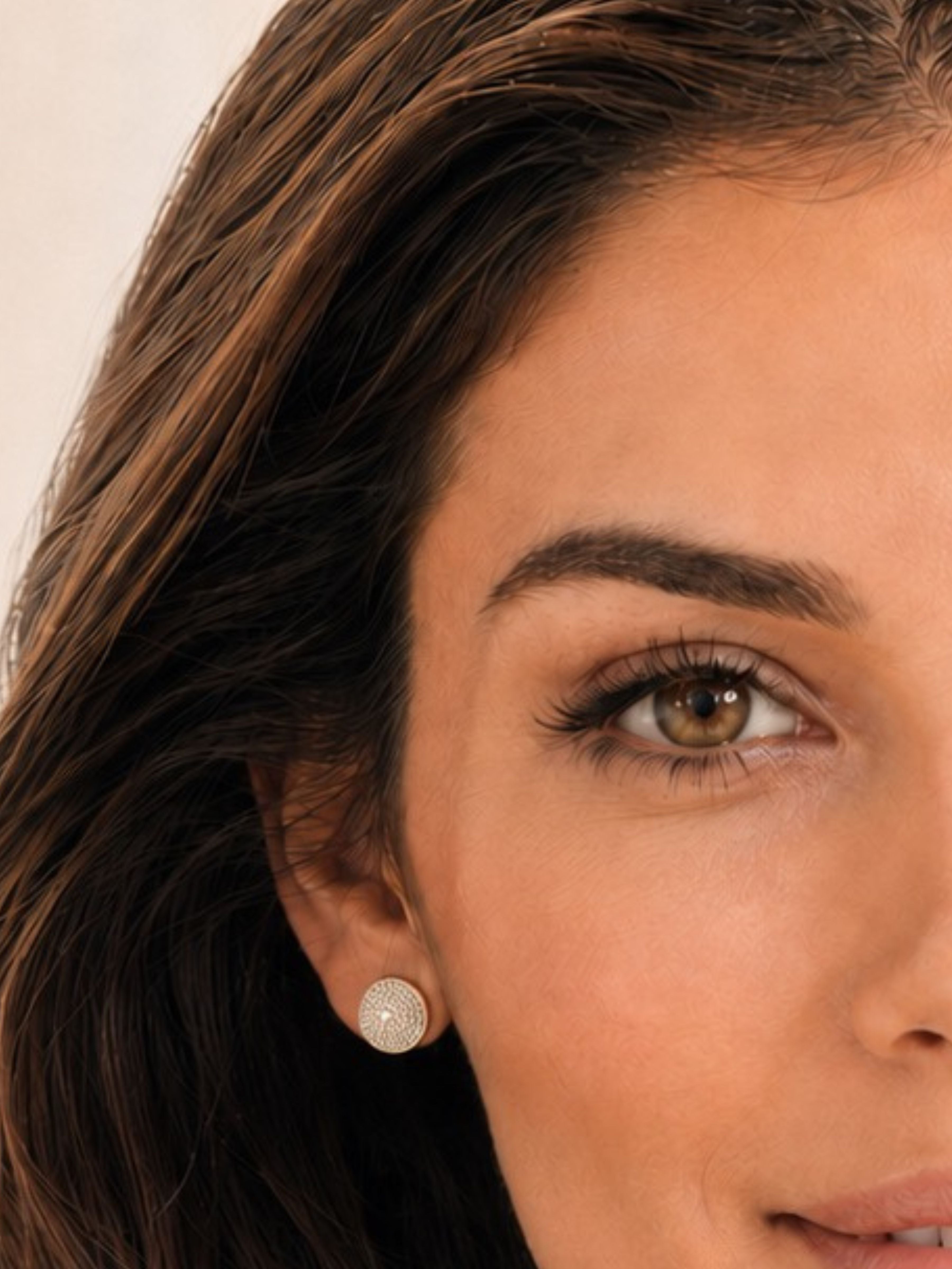 A close-up of a woman's face and ear wearing a small round stud earring with a textured, scalloped silver surface.