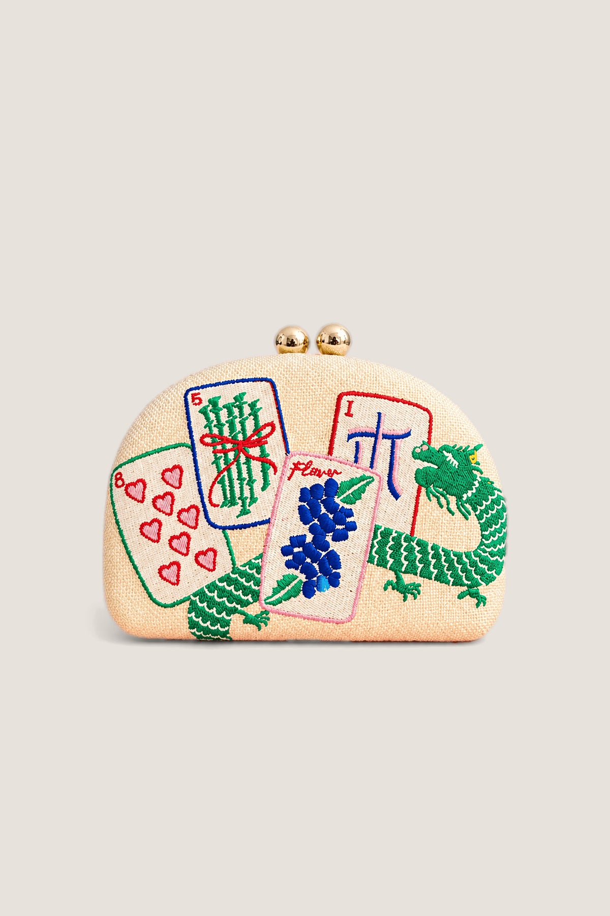 The Lisi Lerch Mahjong Embroidered Clutch in natural straw, embroidered with mahjong tiles and a green dragon, shown front on with its gold ball clasp.