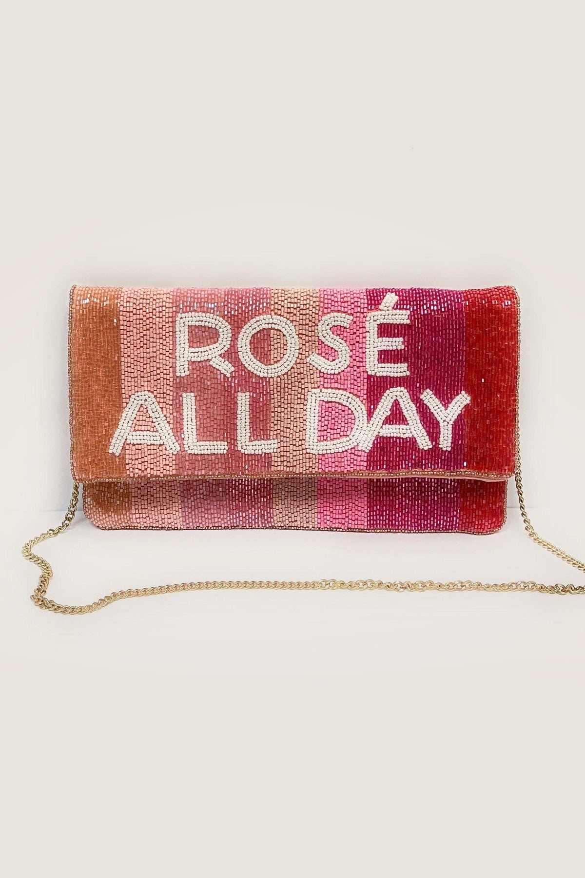 The Rose All Day beaded clutch standing with its gold chain strap draped in front, on a warm greige backdrop.