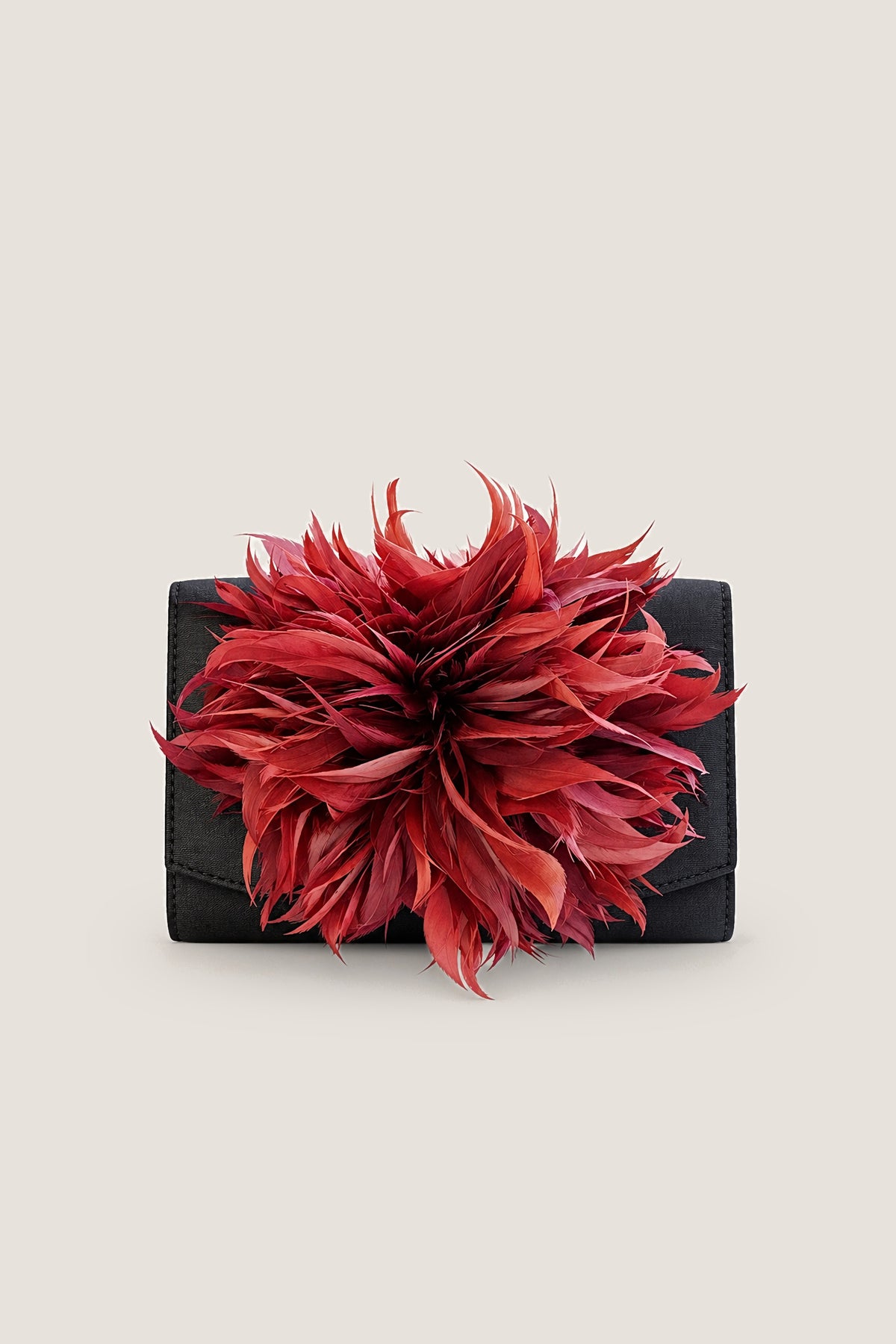 Black Scallop Ruby Feather Clutch, a black faille clutch with a ruby-red feather accent, front view on a warm greige backdrop.
