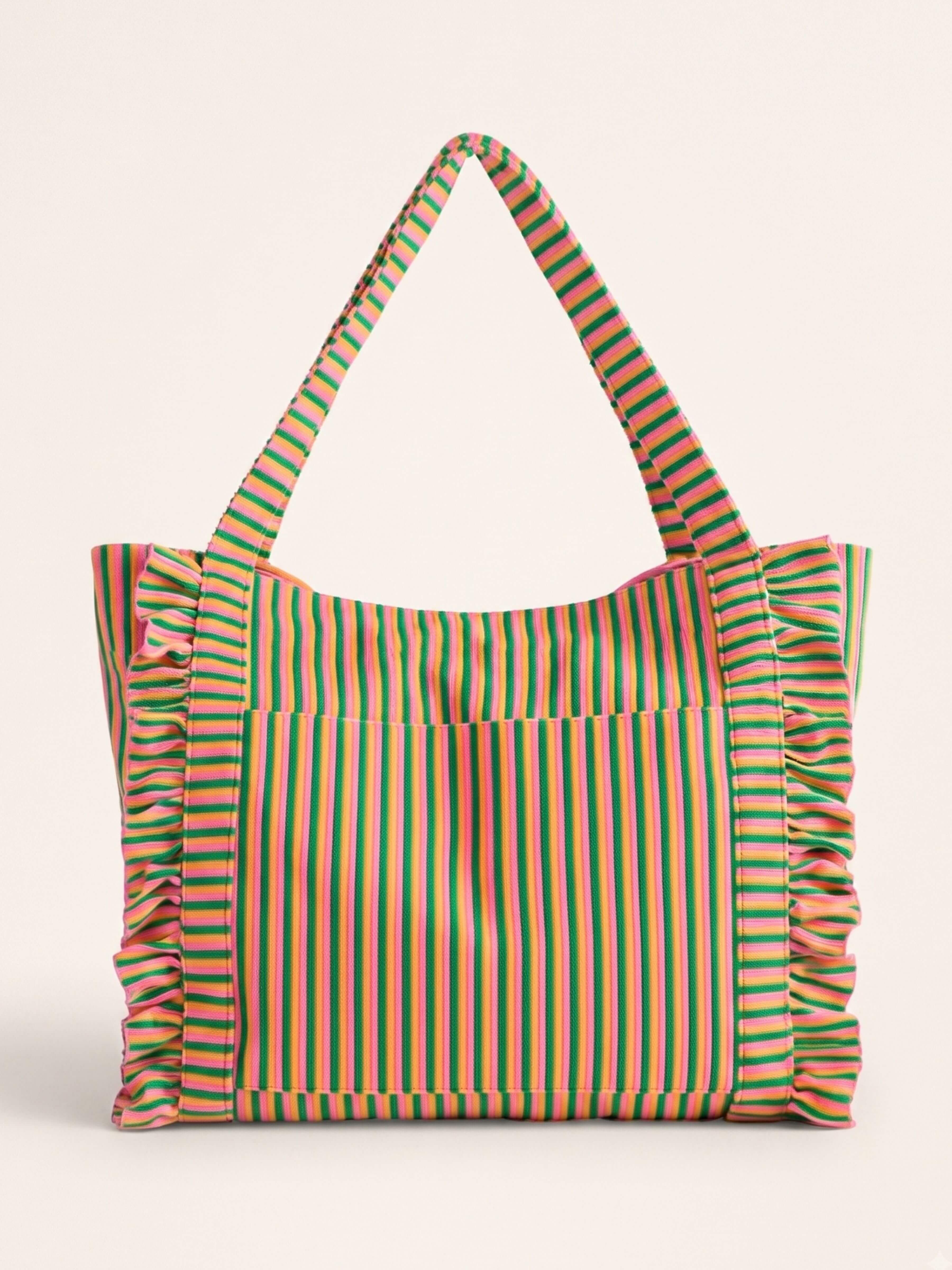 A striped tote bag with ruffled edges and shoulder straps, featuring vertical stripes in green, orange, and pink on a light beige background, set against a solid cream backdrop.